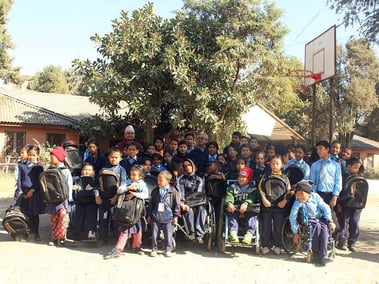 Picture of a girl pushing a boy in the wheelchair in front of the class in Kathmandu